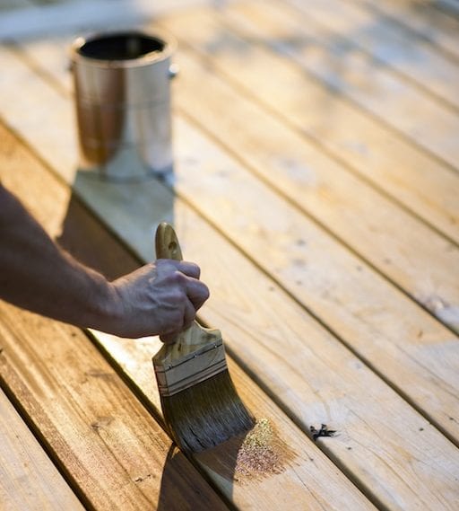 A deck being stained by a homeowner