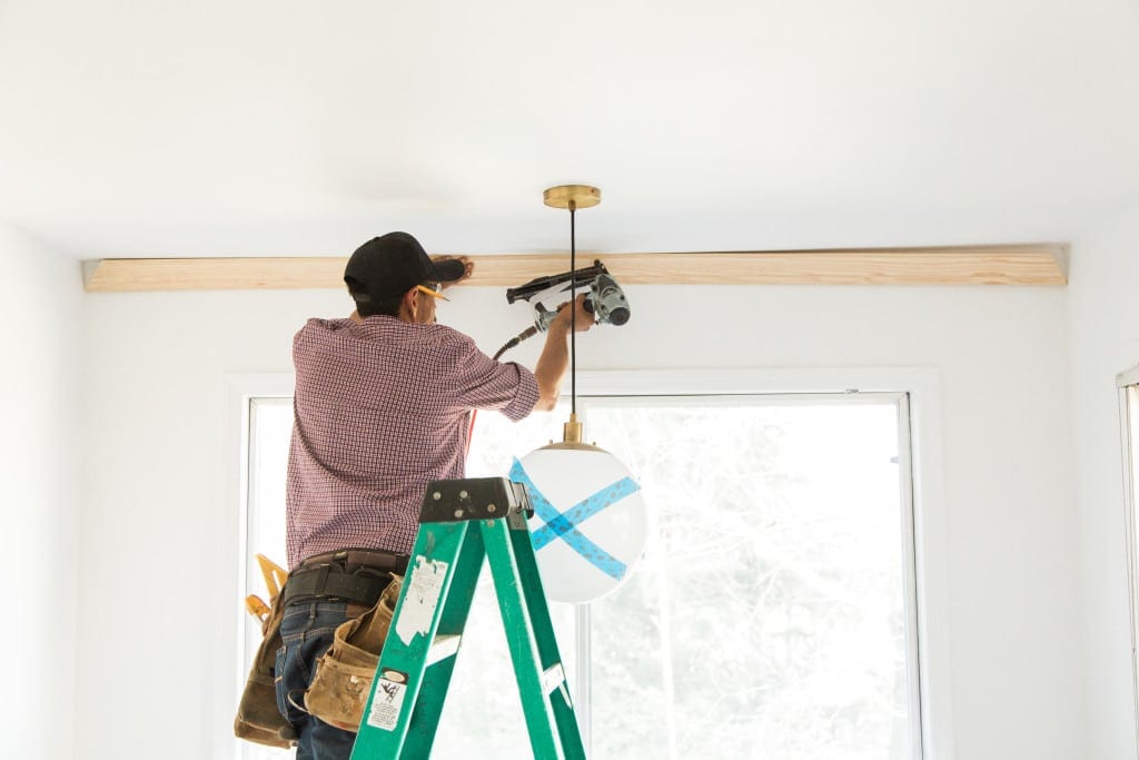 A man installing wooden trim inside a house