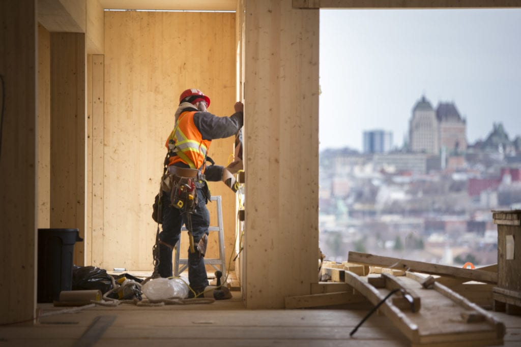 Man assembling mass timber wall in Origine building