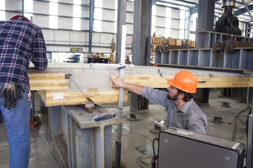 Two people assembling and testing mass timber panel