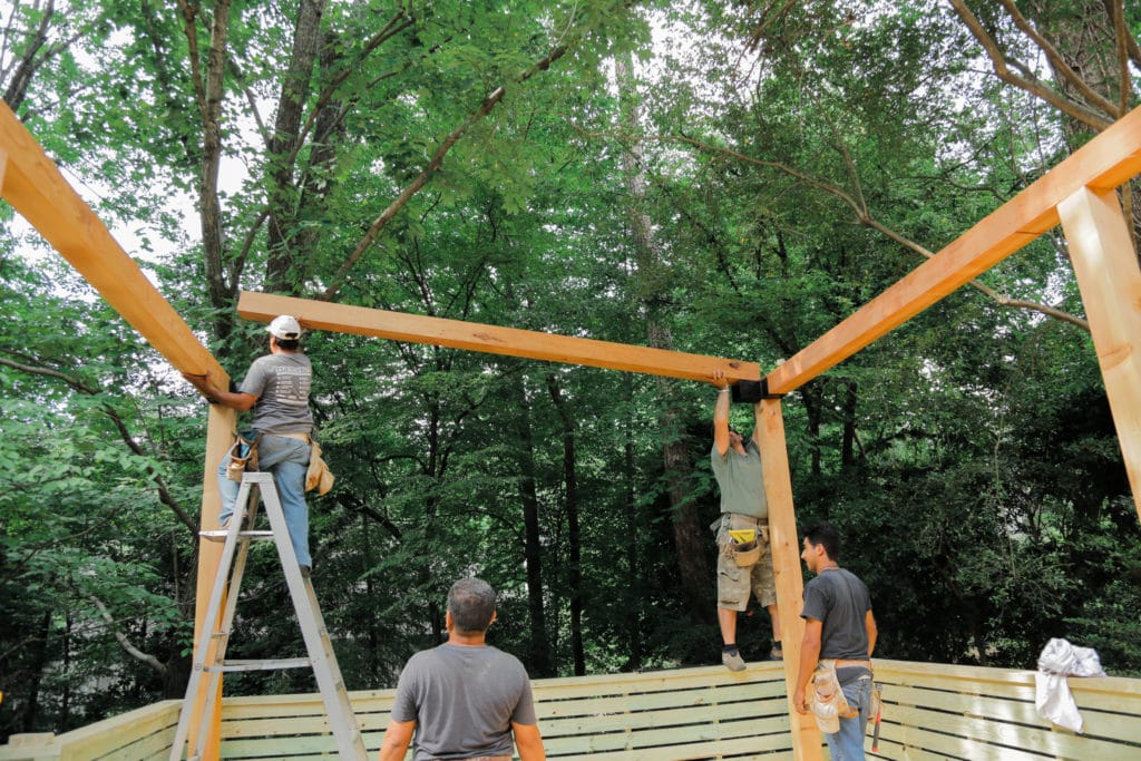 Four men installing an outdoor patio made out of wood