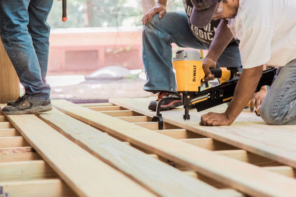 Men installing wooden panels on a deck